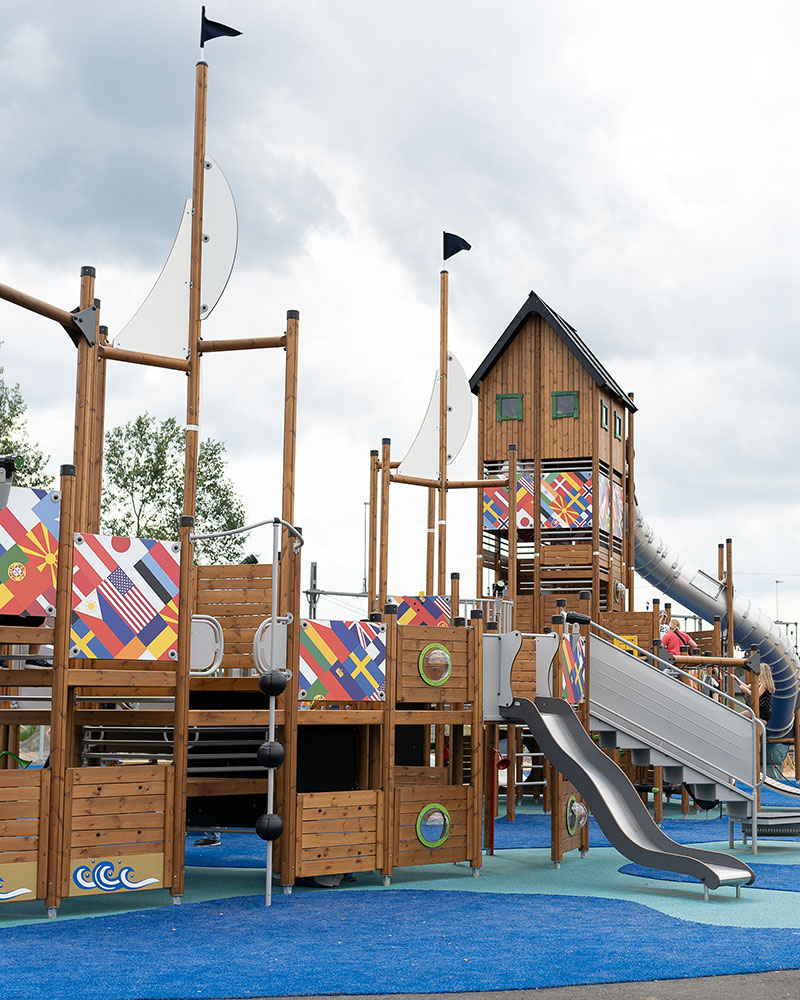 Large themed playground unit with flag panels from around the world. The playground system is wooden.